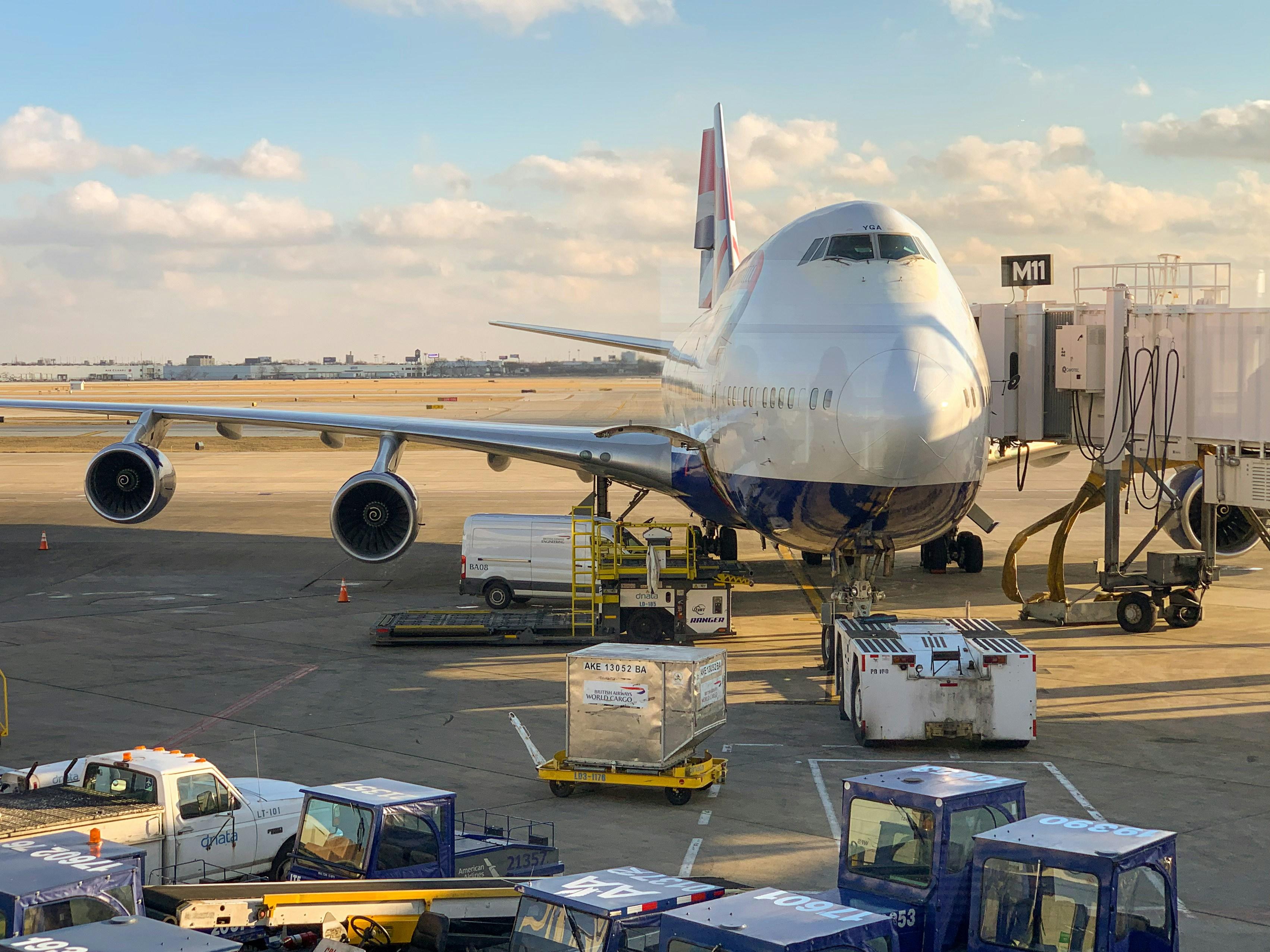 Air freight cargo being handled beside a wide-body aircraft at an airport.